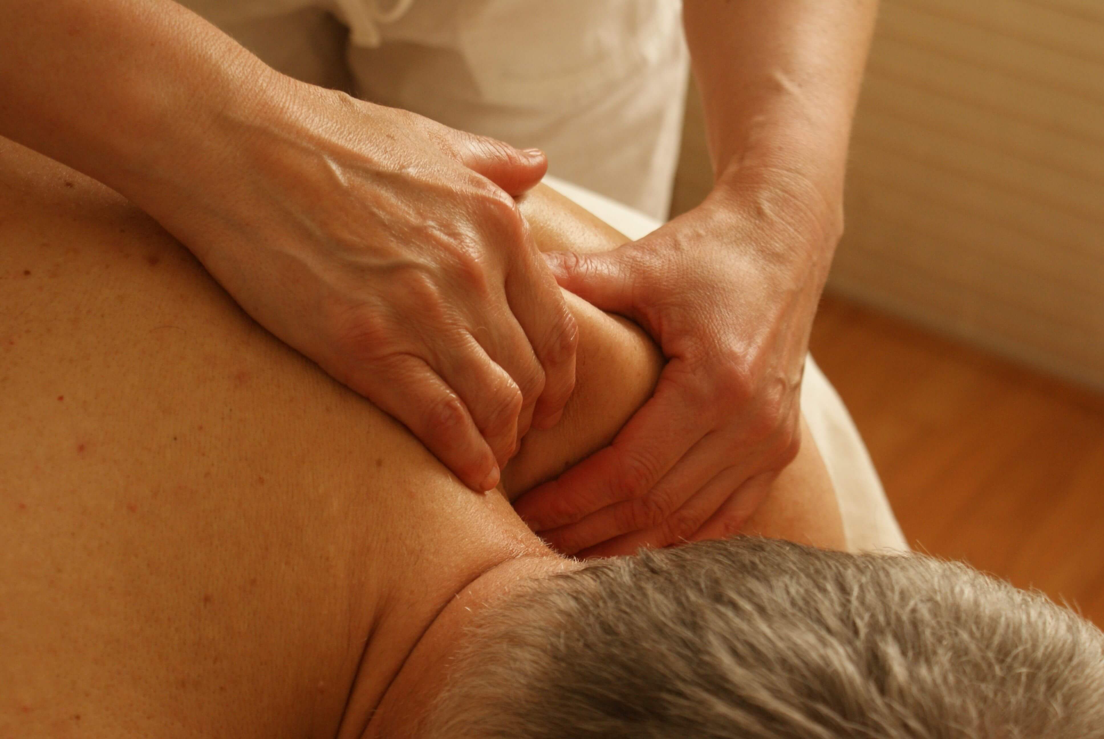 Therapist using a forearm to apply slow pressure across the upper back during a deep tissue massage