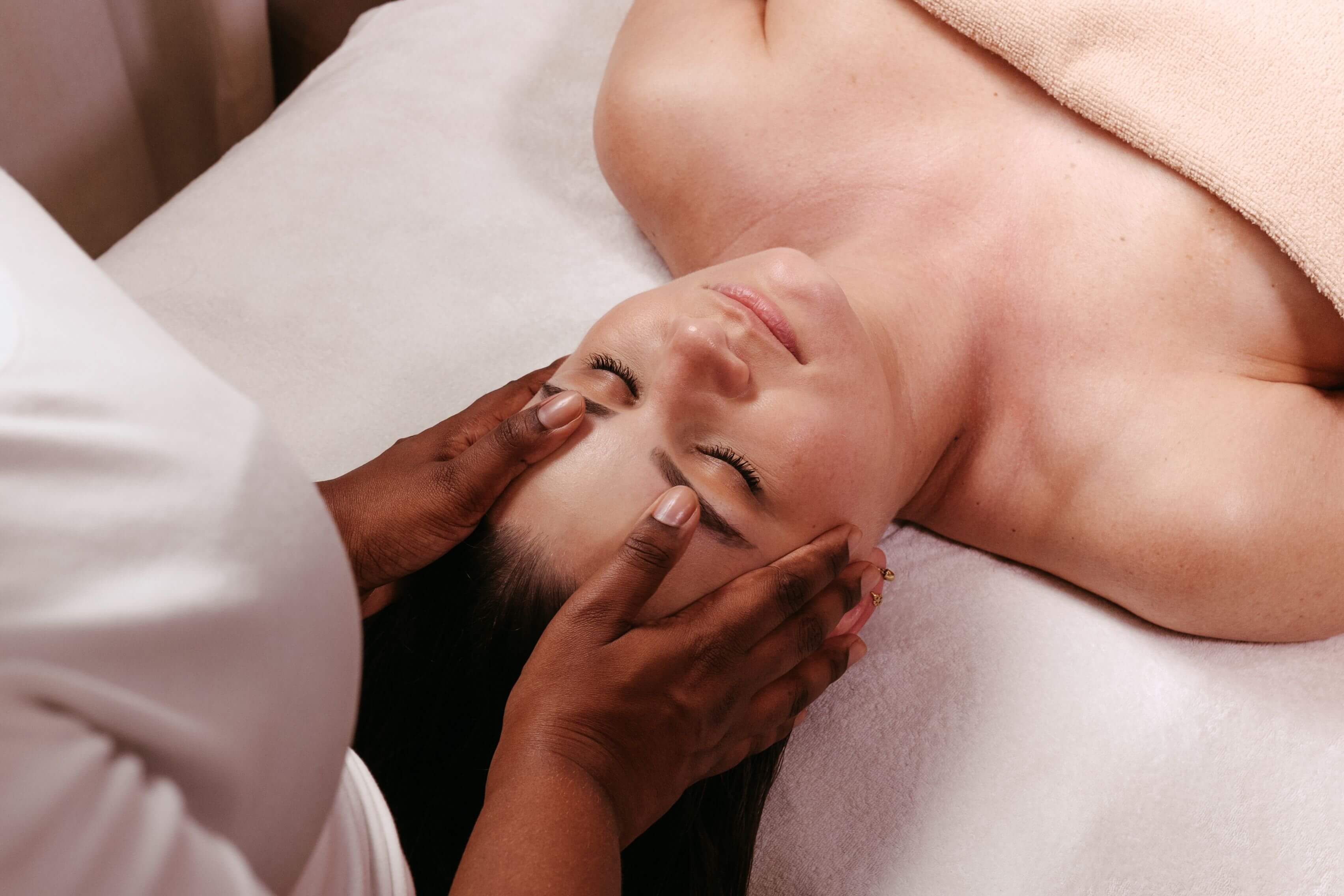 A person sitting upright while their scalp is massaged