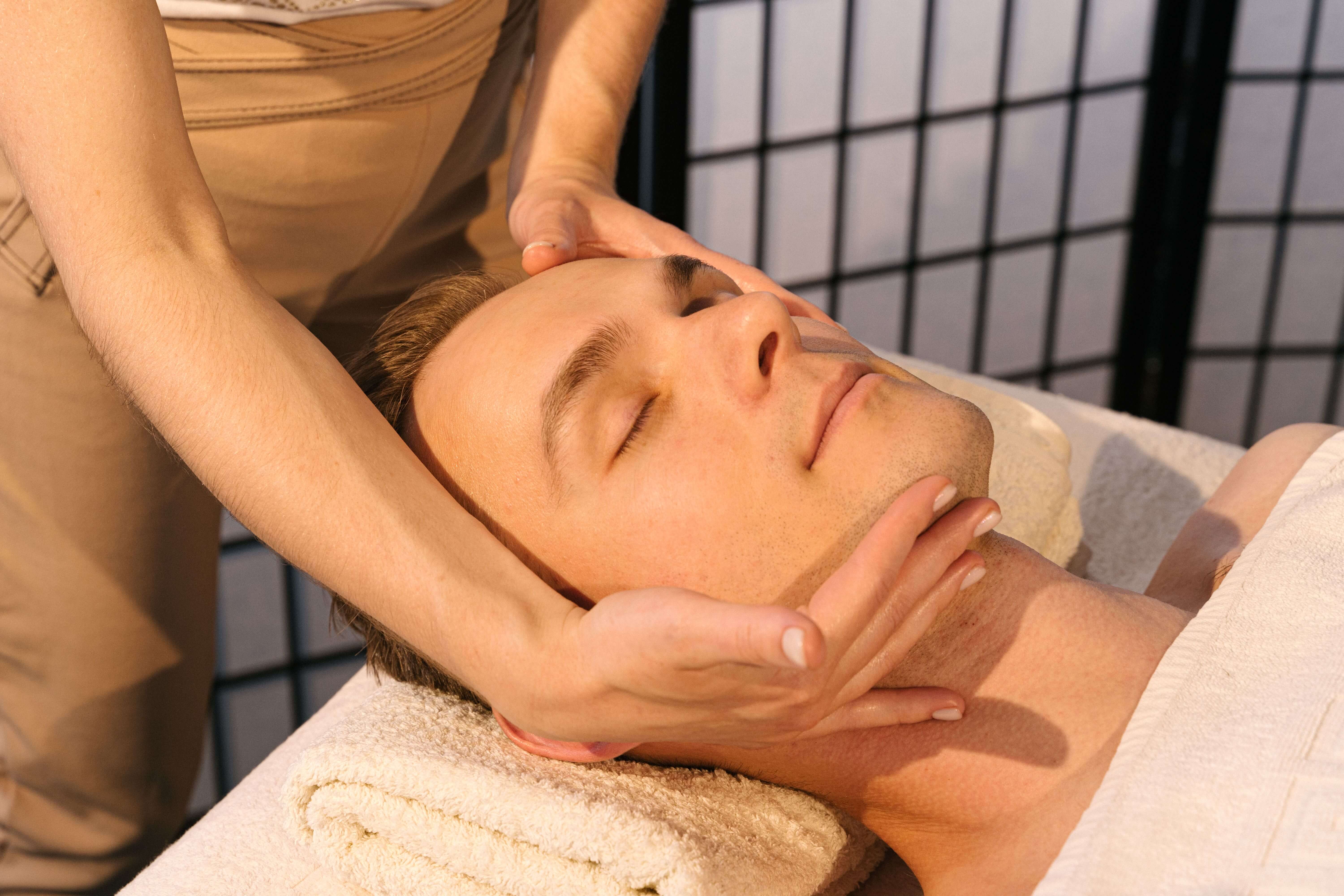 Hands working into the tops of the shoulders of a seated client